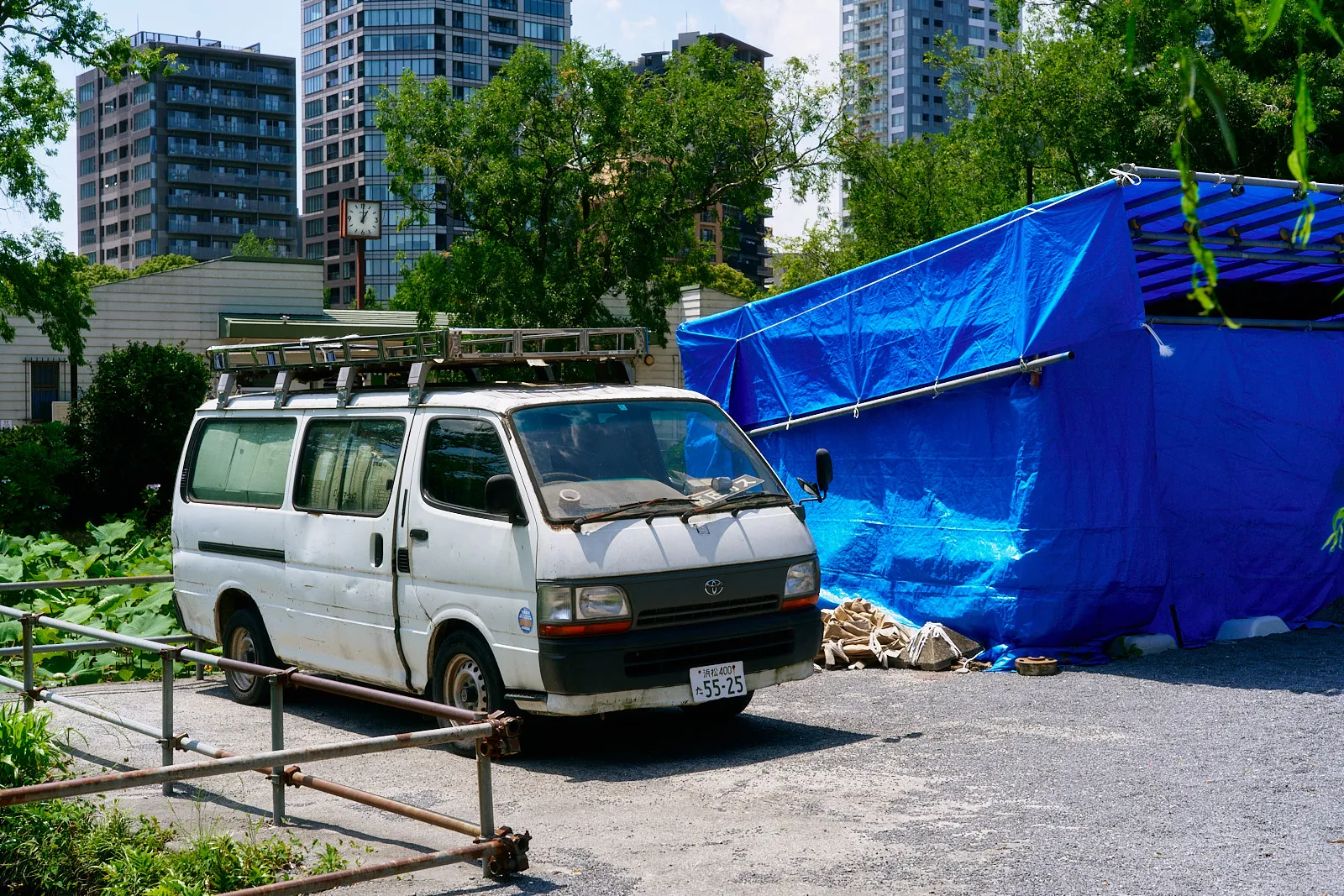 Photo of a white truck near a structure covered with blue cover somewhere in Tokyo